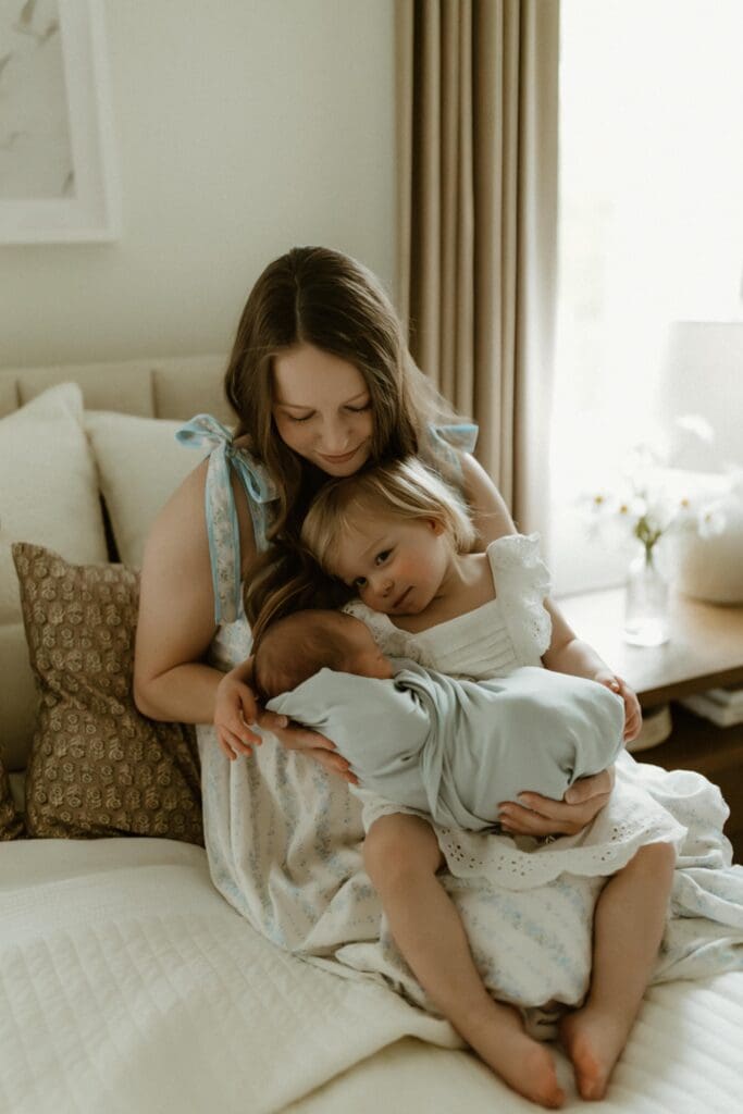 mother and daughter holding a newborn baby during lifestyle photoshoot