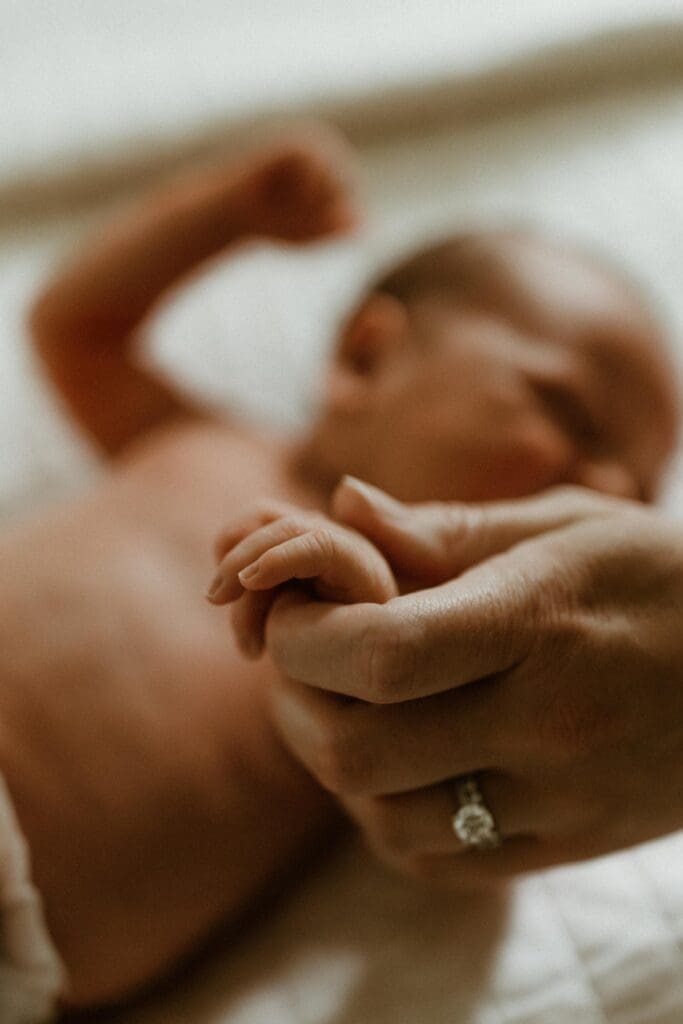 detail photograph of a newborn baby's hand wrapped in moms hand