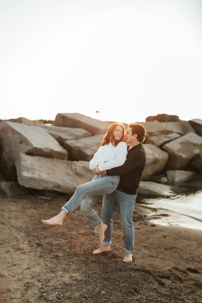 playful candid engagement photo of couple laughing on the beach