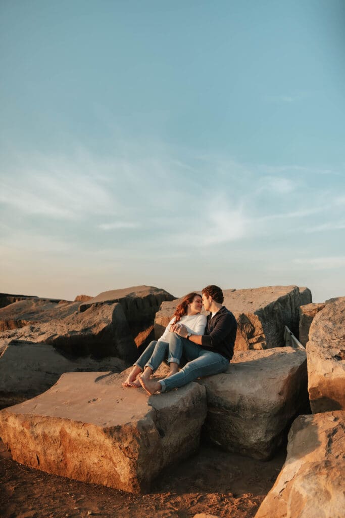 couple sitting along rocks with golden light on them