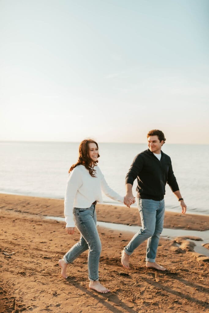 engaged couple walking by lake michigan