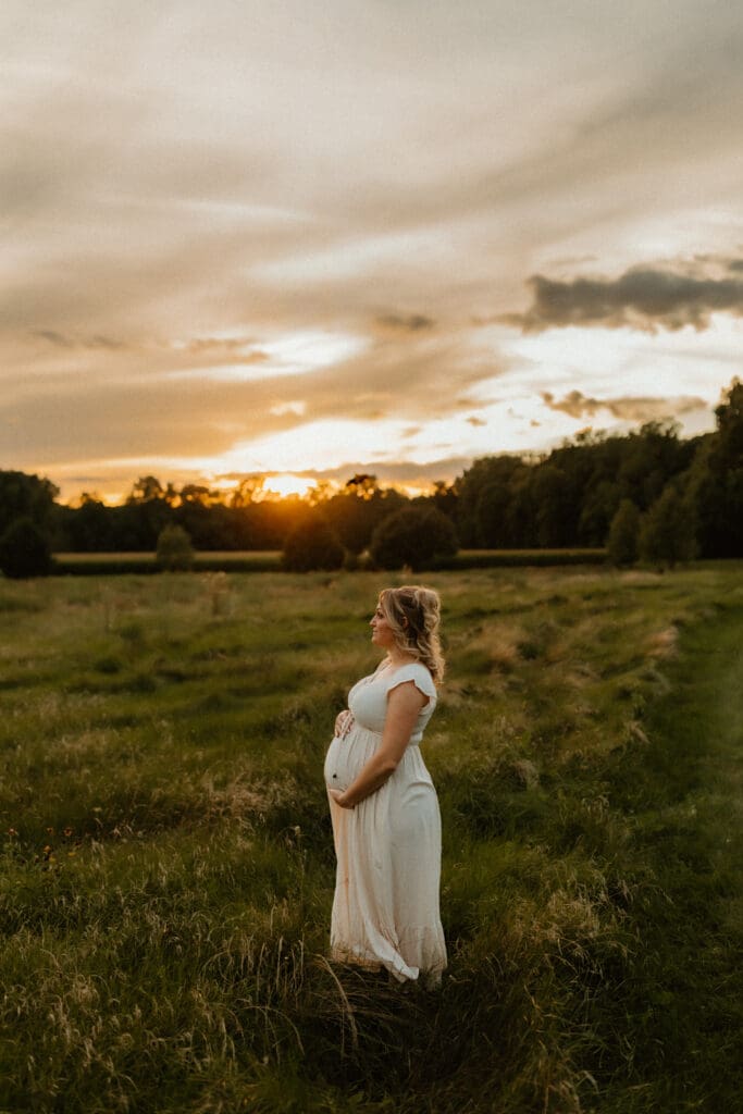 pregnant mom stands in field at sunset photography session in south bend indiana