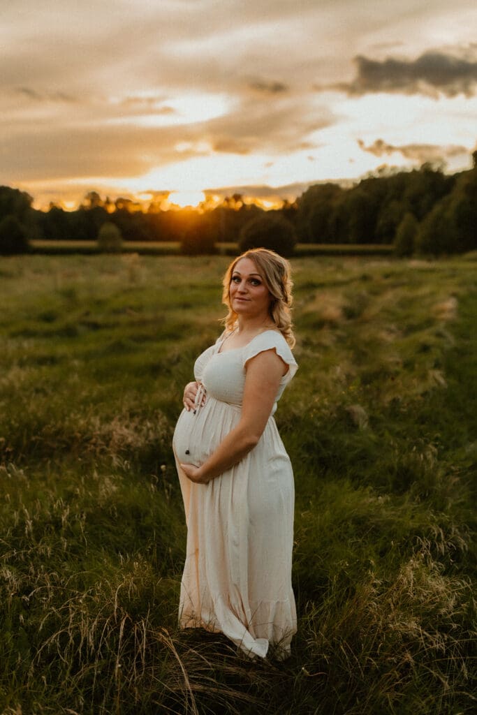 a maternity photo at sunset in an open field