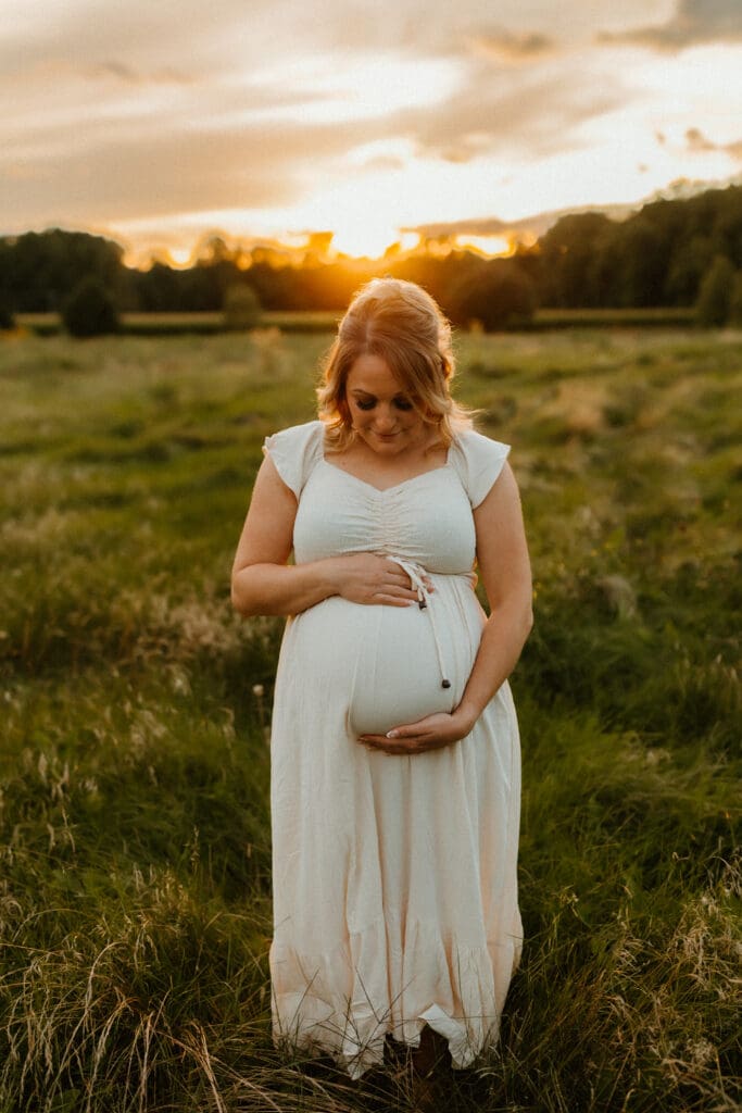 mom looking at her belly during maternity photoshoot in south bend