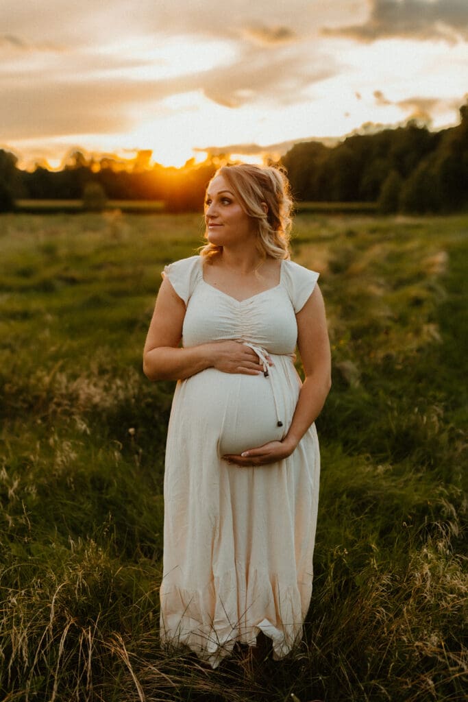 south bend maternity photo of mom in grassy field at sunset 
