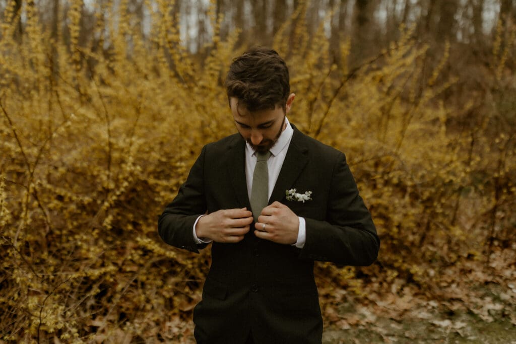groom fixing his tux during wedding portraits