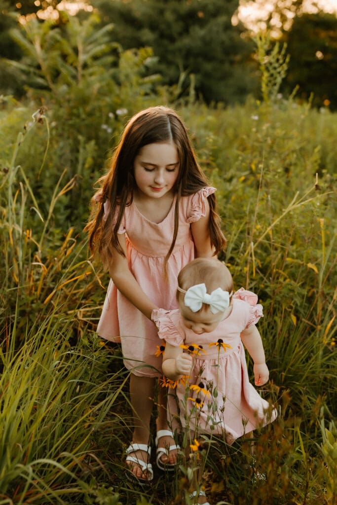 sisters smelling spring flowers during elkhart photoshoot