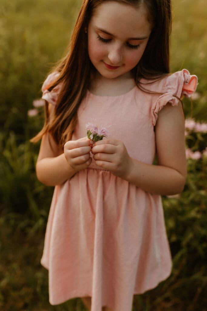 child holding a flower in field during elkhart photoshoot