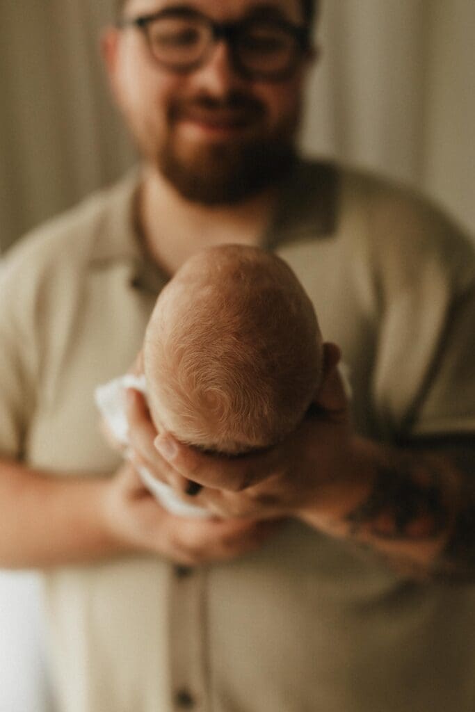 dad holding newborn baby in natural setting