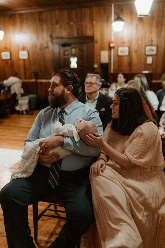 parents holding baby during baptism ceremony