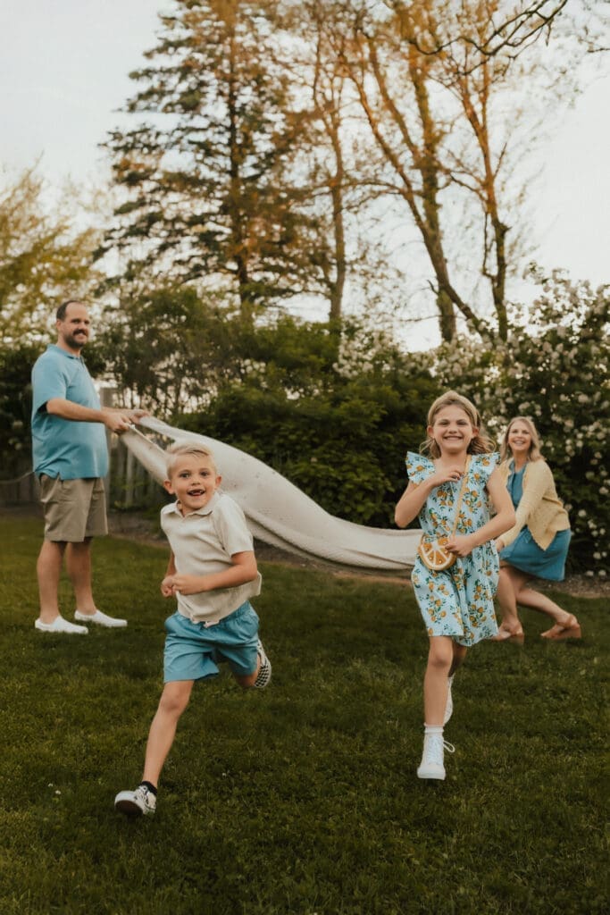 children running under a blanket during family photo session in elkhart county
