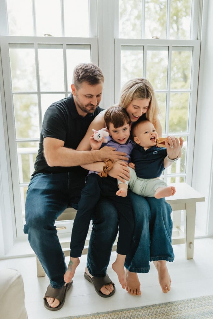 family sits on bench by window in union pier michigan beach house
