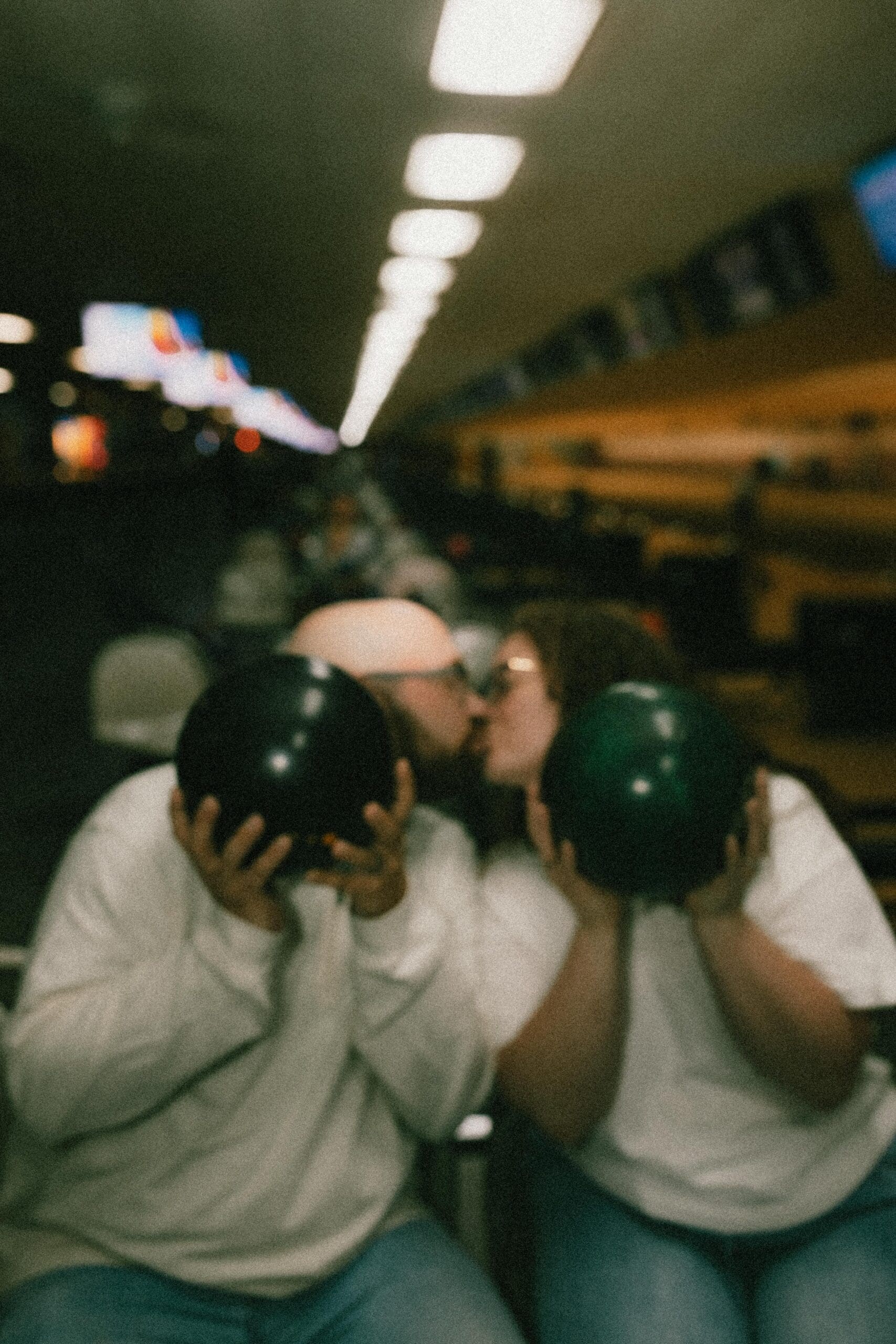 couple kissing behind bowling balls in south bend engagement session