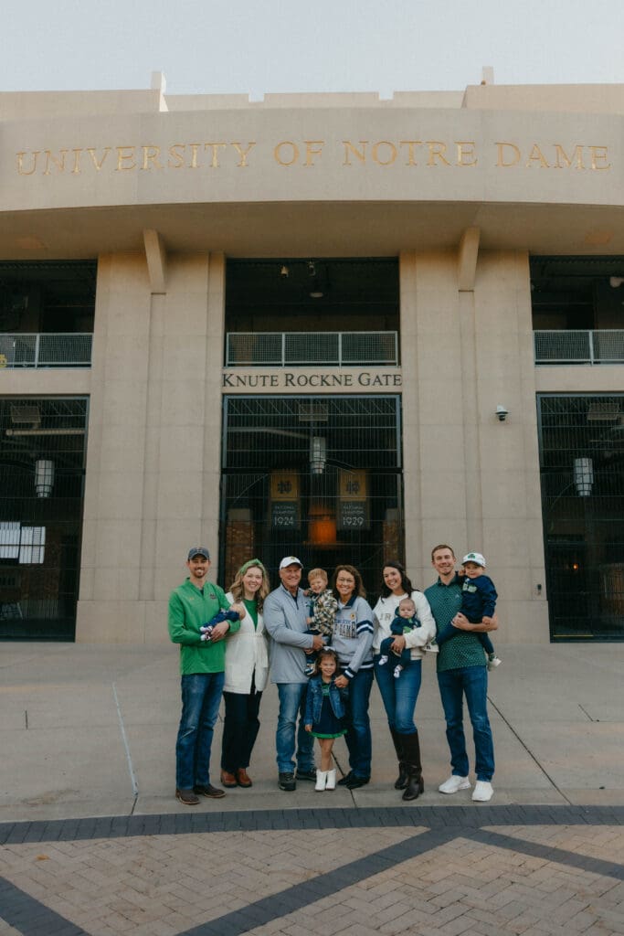 Extended family wearing navy and green outside Notre Dame Stadium’s Knute Rockne Gate.