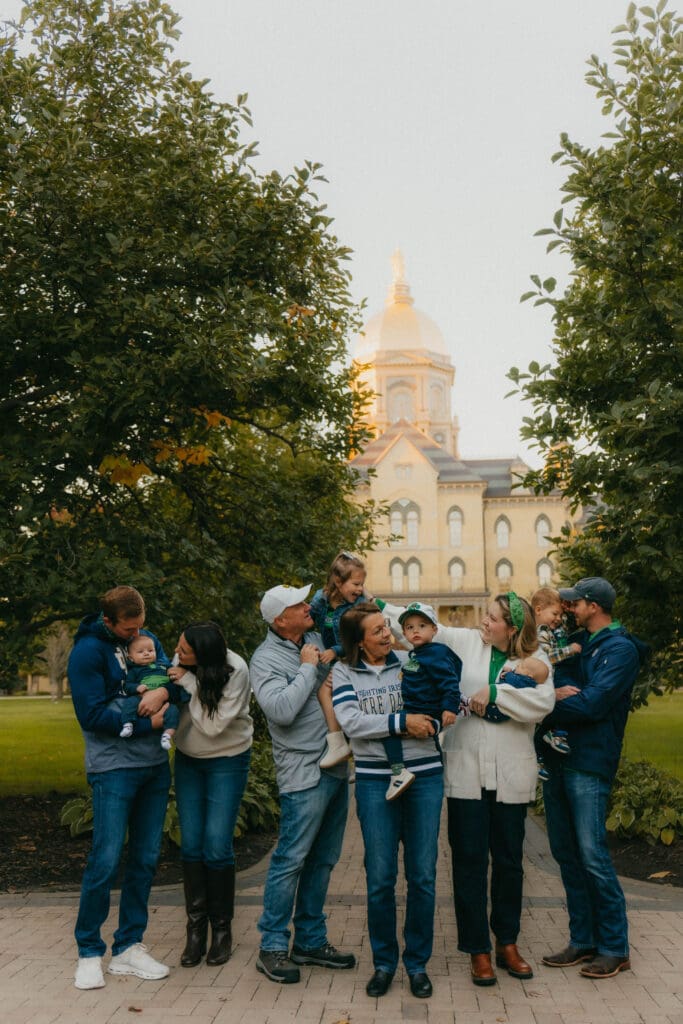 Extended family laughing and holding their children in front of Notre Dame’s Golden Dome.
